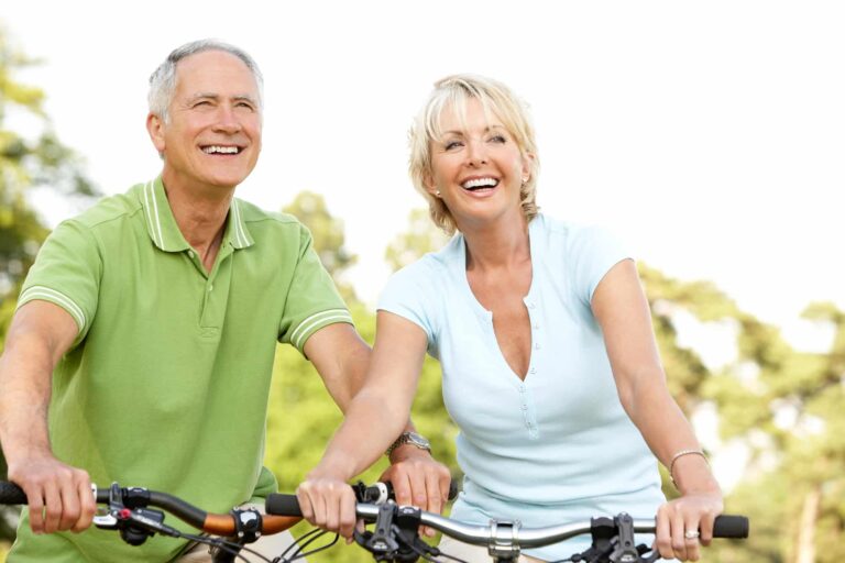 A happy senior couple riding bicycles outdoors, enjoying an active and healthy lifestyle in a sunny park.